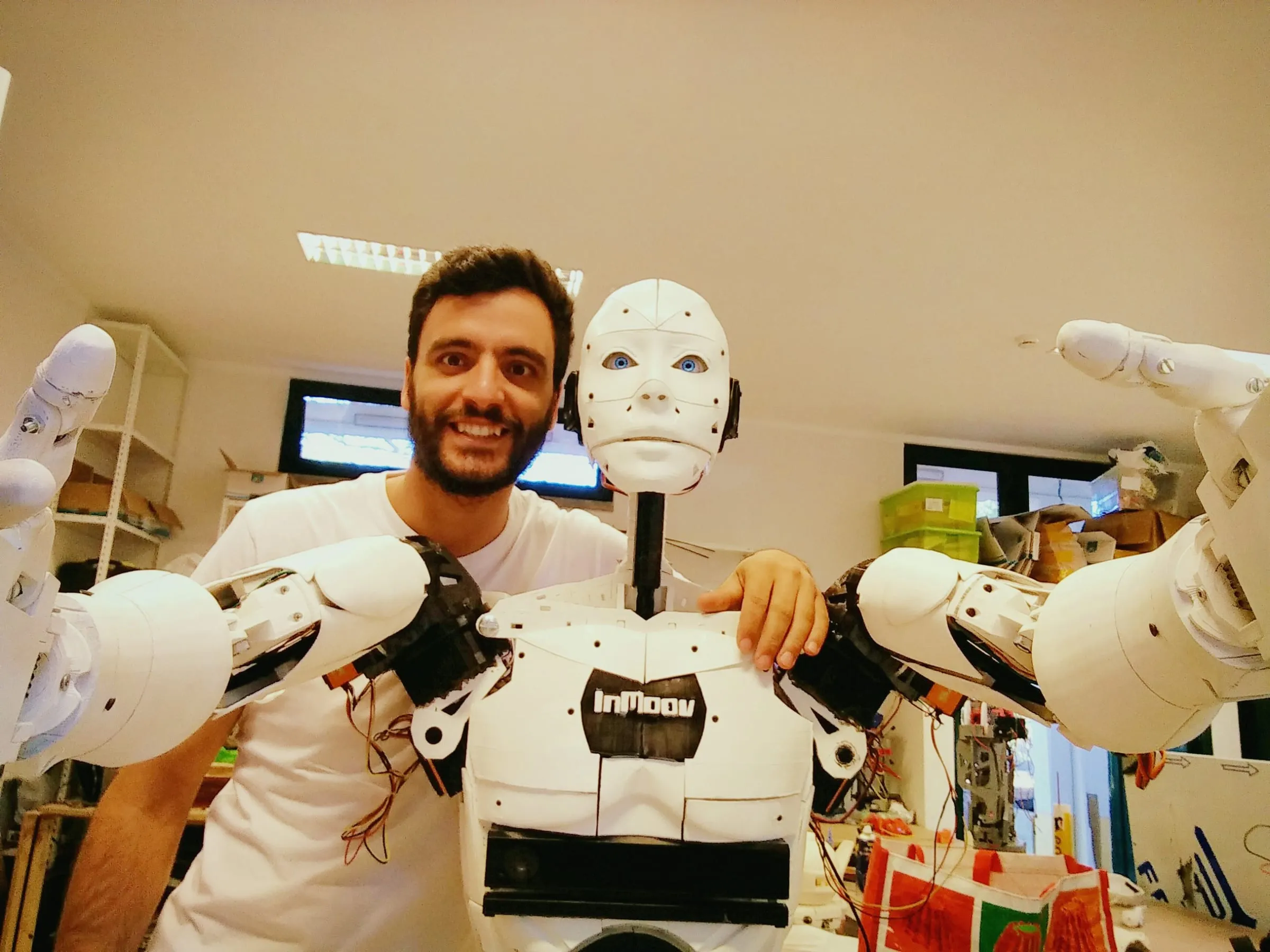 Luís Carlos next to the life-size white 3D-printed InMoov humanoid robot