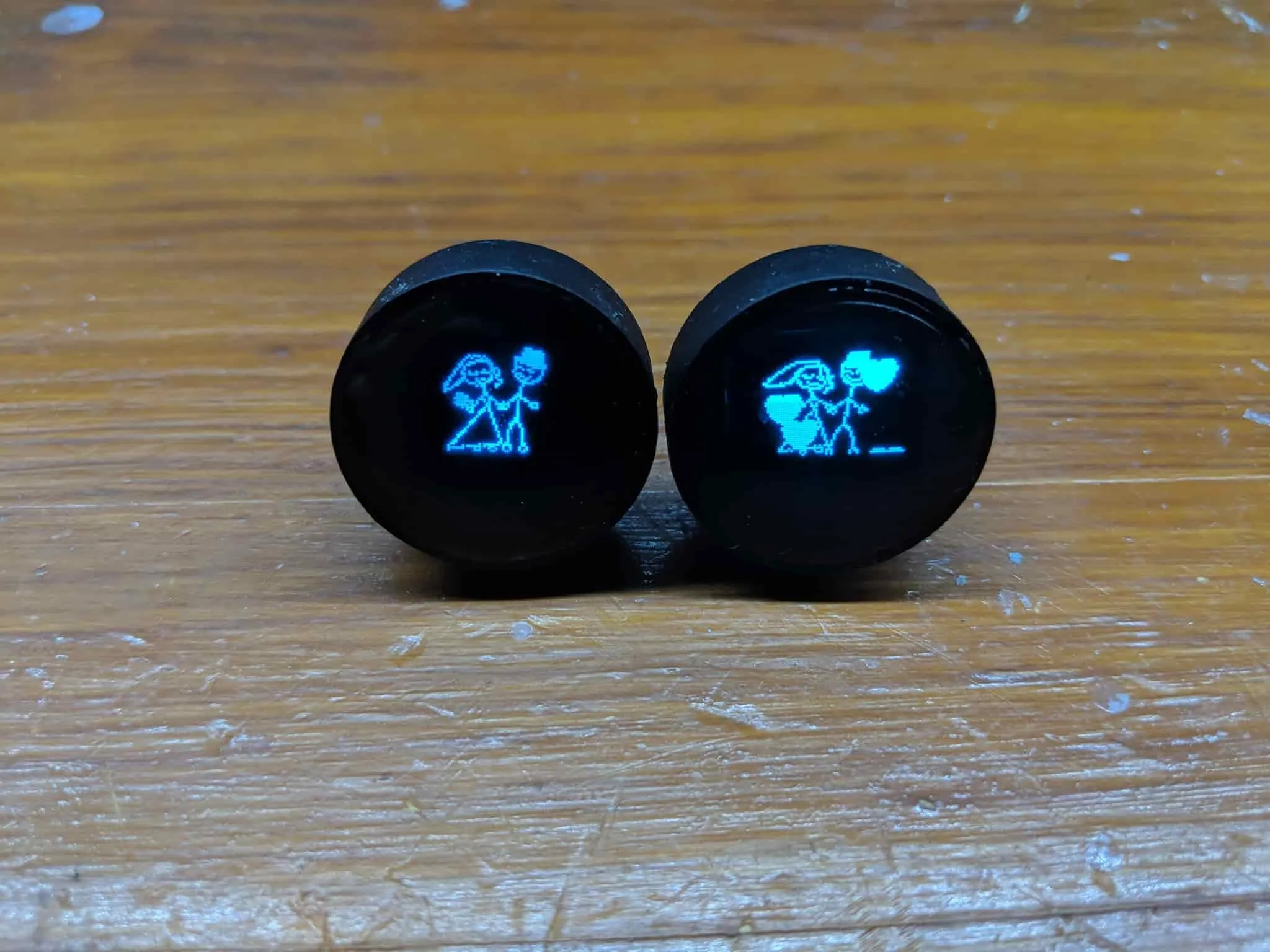 The pair of smart cufflinks with their OLED screens on