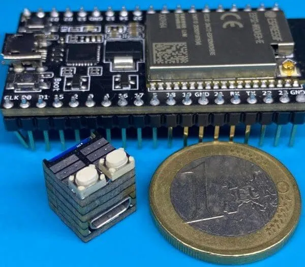The cube next to a standard ESP32 dev board and a coin