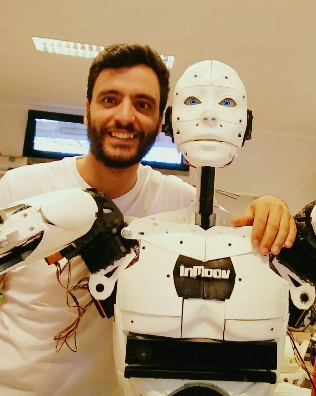 Luís Carlos smiling next to InMoov, the life-size 3D-printed humanoid robot he built